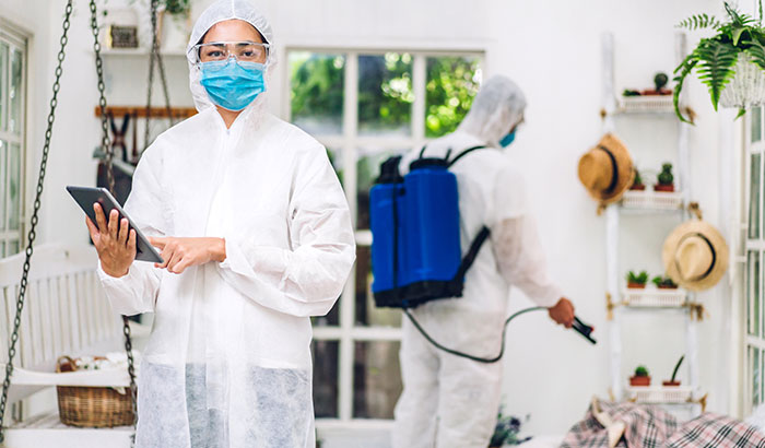 A woman in a protective suit and mask stands in a room with a man in a suit and mask.