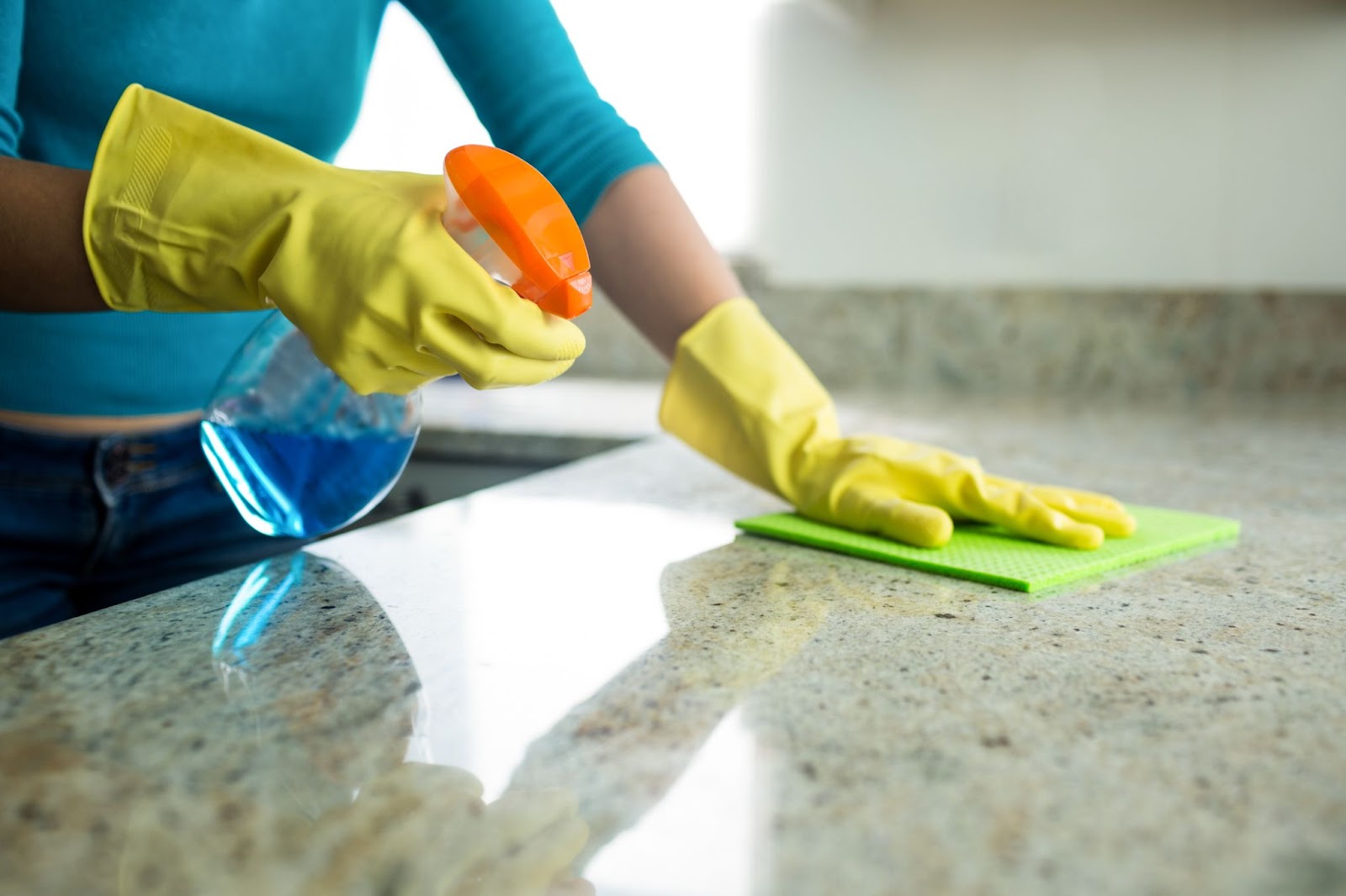 A person wearing gloves and scrubbing a bathtub during a deep cleaning session in a home