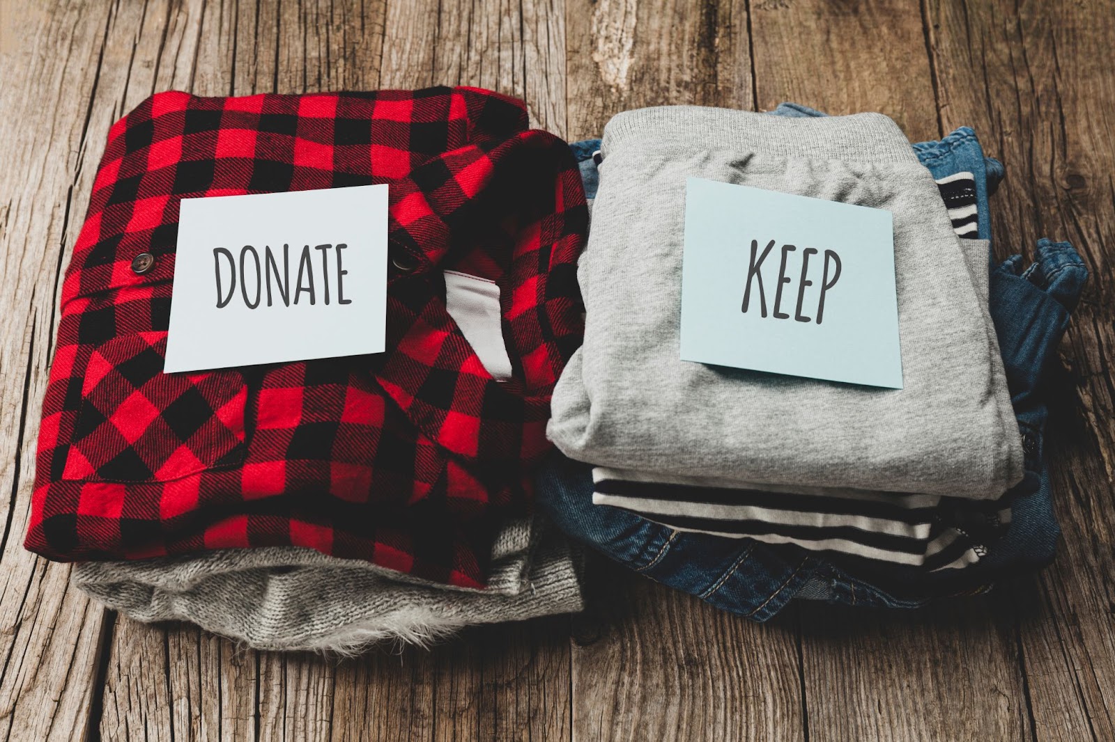 Clothes with donation and keep sign on wooden background