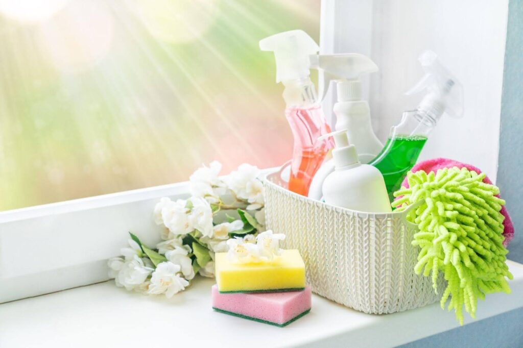 A variety of colorful cleaning products arranged on a window sill