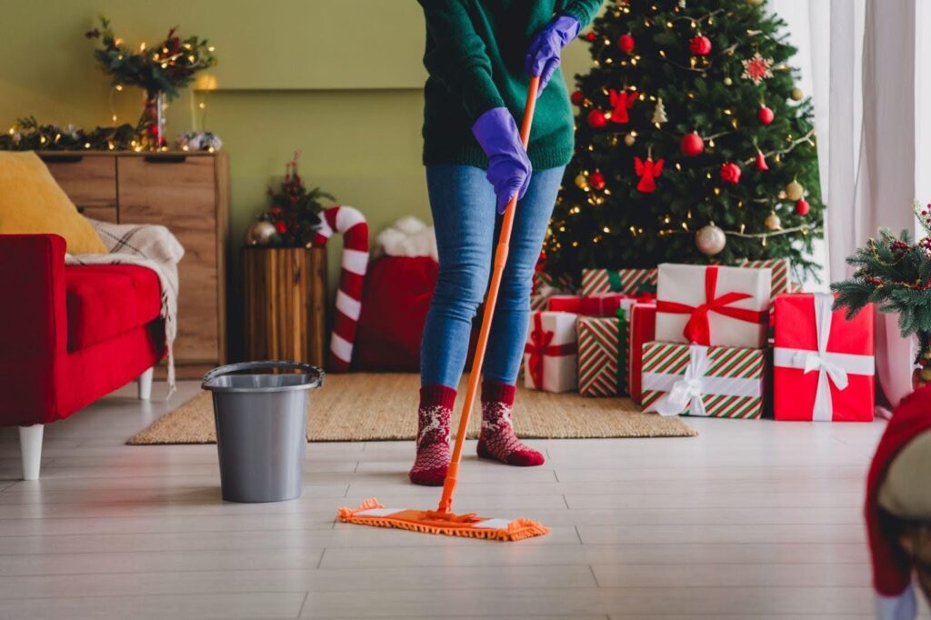 A woman in purple gloves sweeps the floor, focused on cleaning