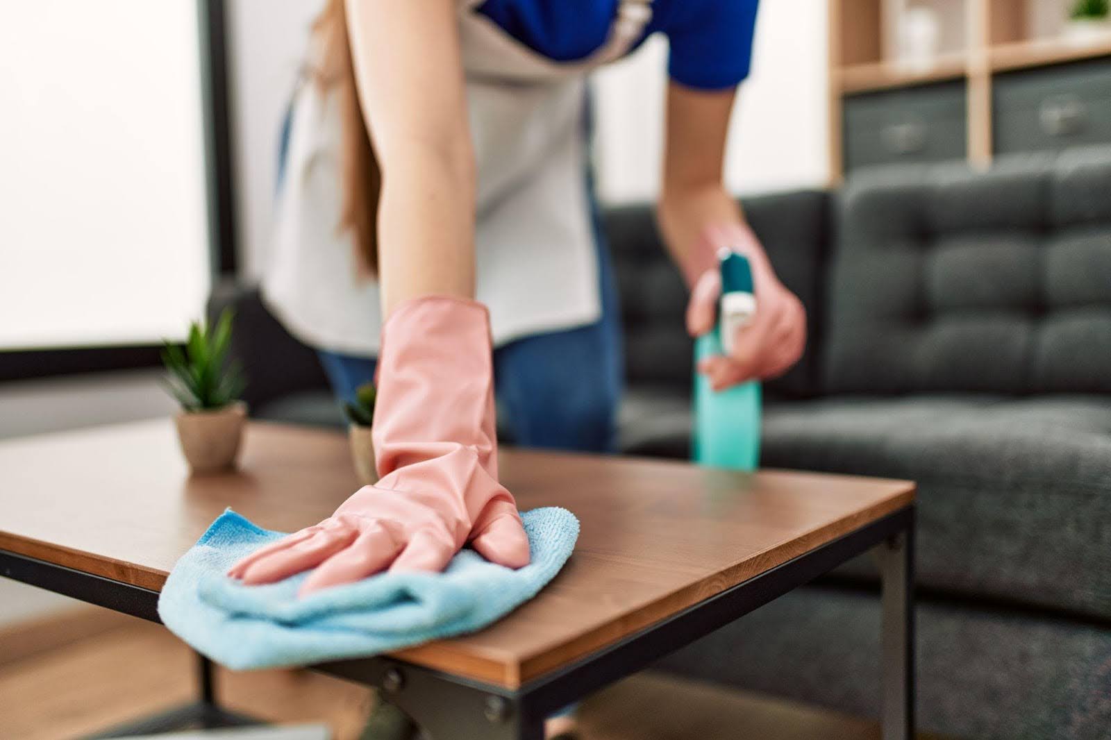A woman scrubbing a table with a sponge showcasing her cleaning efforts in a well-lit dining area