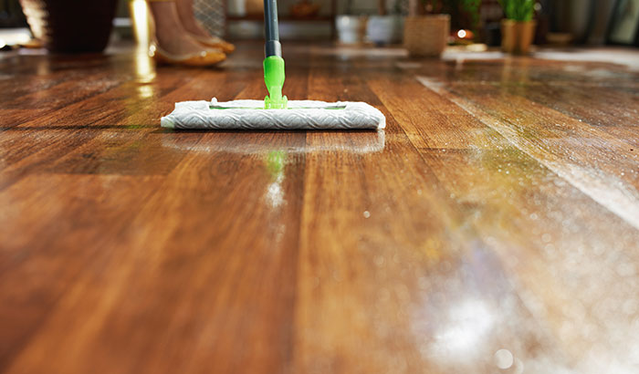 A person mopping a wooden floor to keep it clean and shiny.