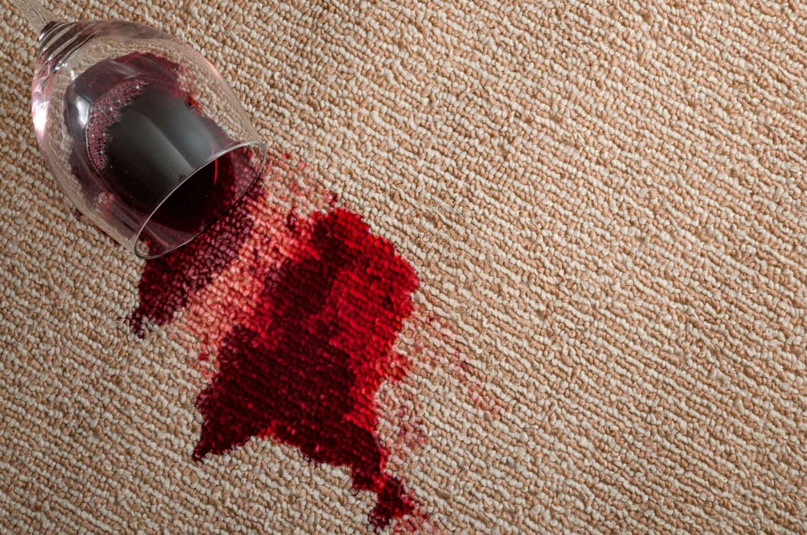 Red wine spilled on carpet, creating a stain. Image relates to carpet stains, removing stains from carpet, cleaning carpets.