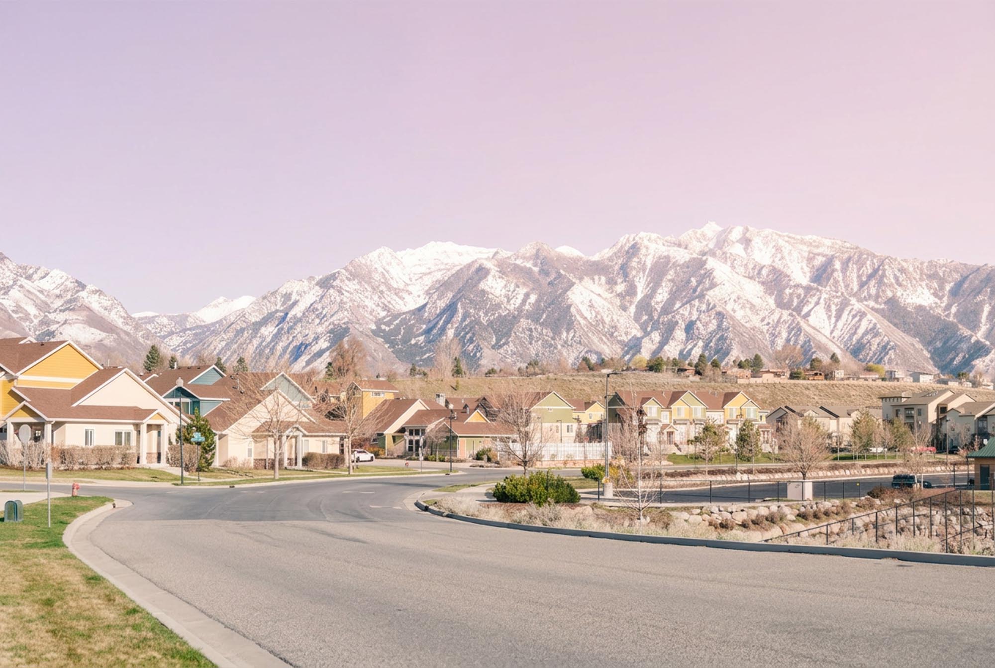 A scenic street in Park City featuring houses with mountains rising in the background.